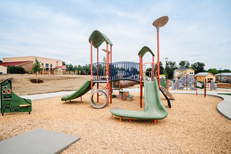 A playground with a green slide and a red and white slide.