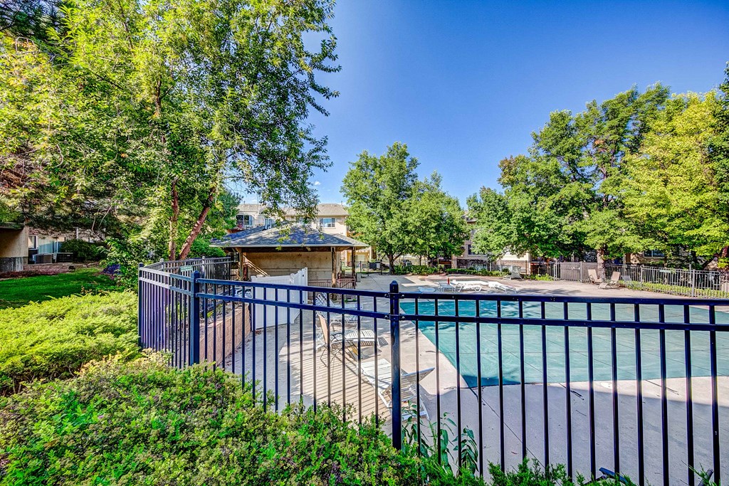 a fenced in swimming pool with a gazebo and trees