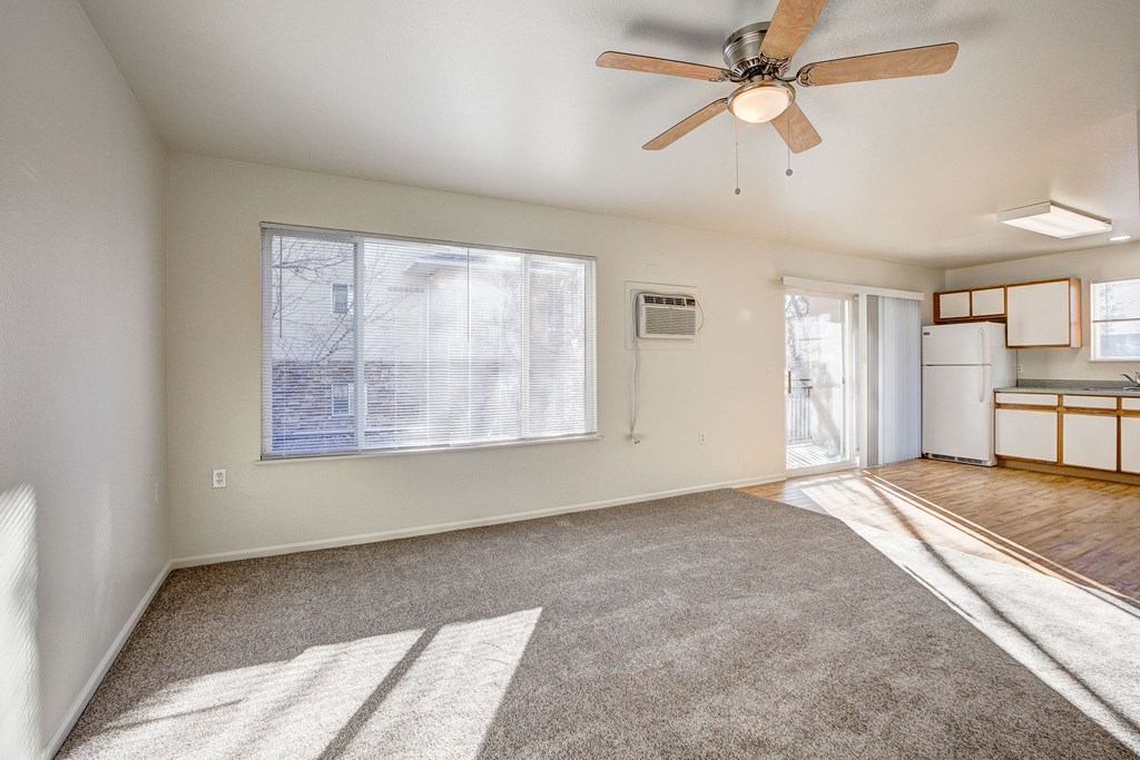 A room with a ceiling fan and a window with blinds.