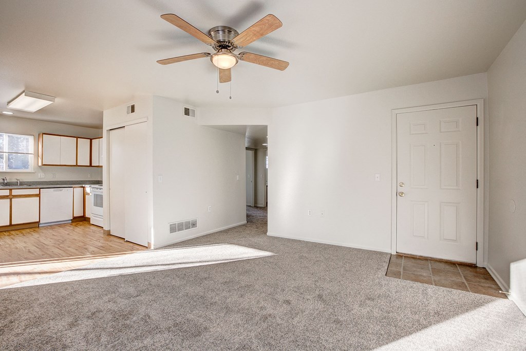 A room with a ceiling fan and carpeted floor.