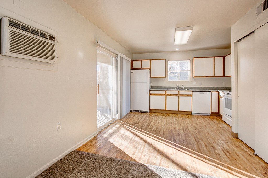 A kitchen with white appliances and wooden floors.