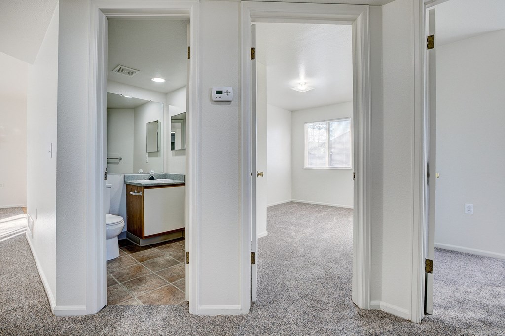 A white bathroom with a toilet, sink, and mirror.