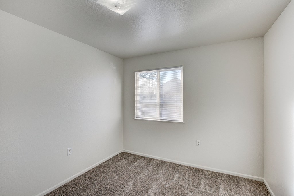A room with a window and carpeted floor.