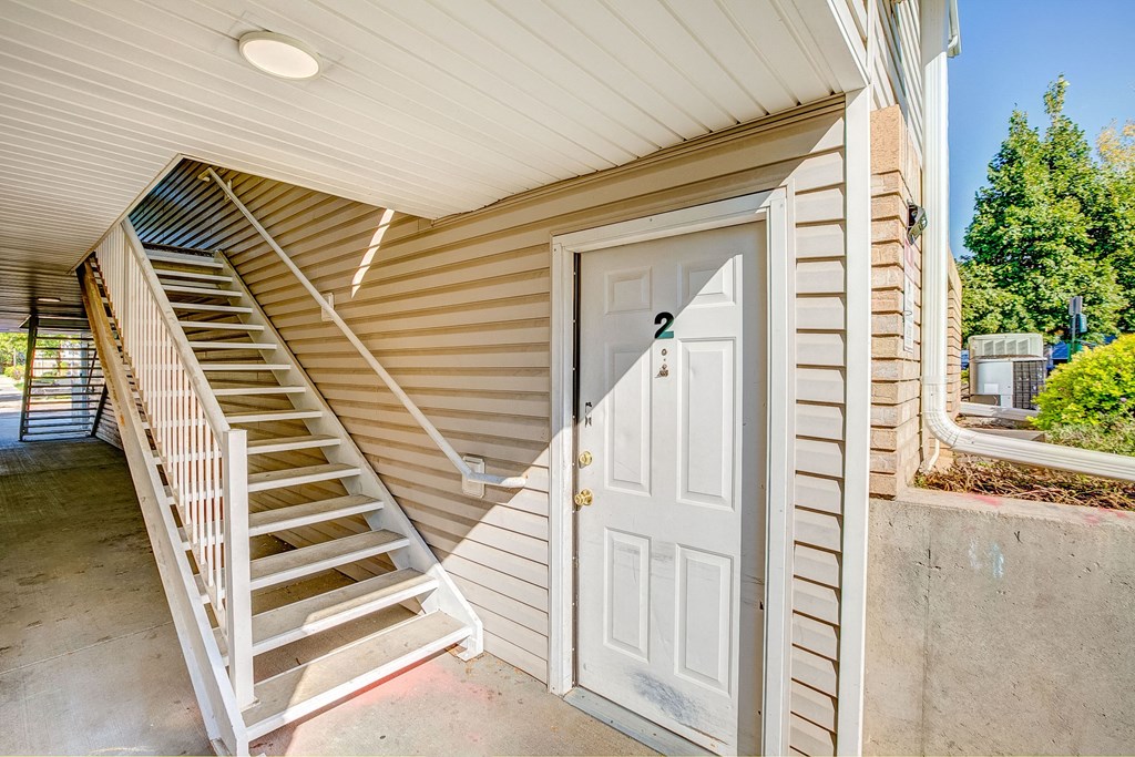 the front door of a house with stairs and a white door