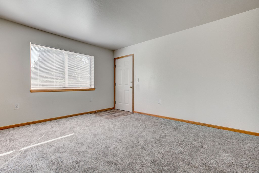 the living room of a home with carpet and a window