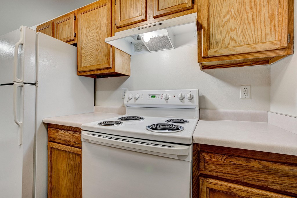 the kitchen has a white stove and refrigerator and wooden cabinets