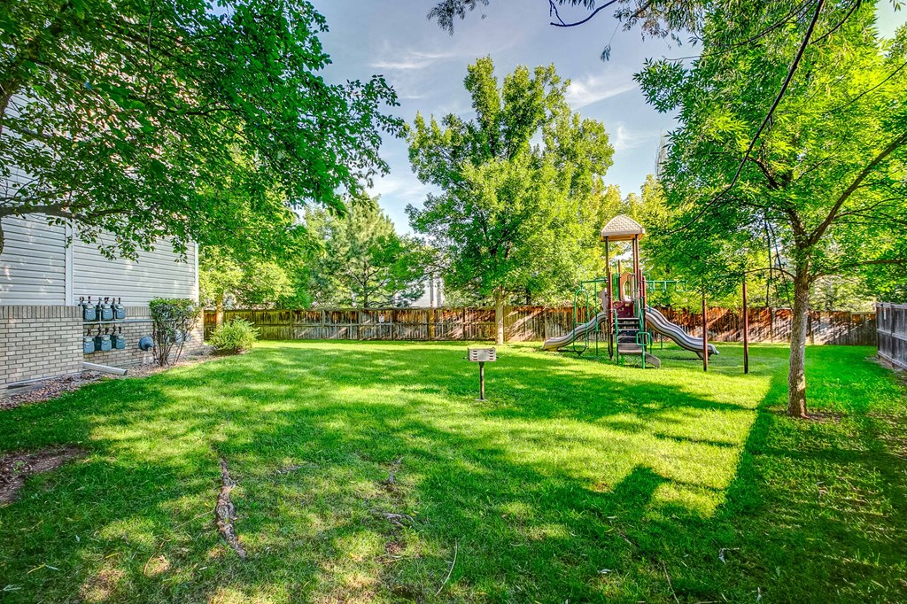 a backyard with a swing set and a green lawn
