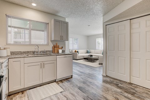the kitchen and living room of an apartment with white cabinets and a counter top