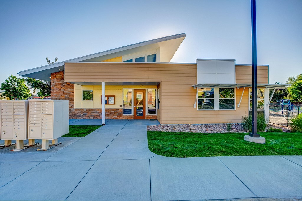 a sidewalk in front of a building with a driveway and grass