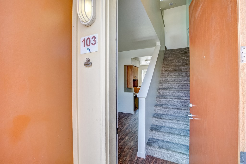 the view from the hallway of a house with a staircase and a carpeted floor