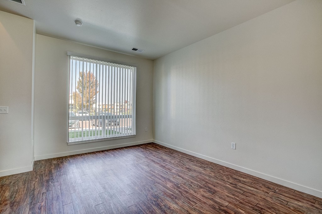 an empty living room with wood flooring and a large window