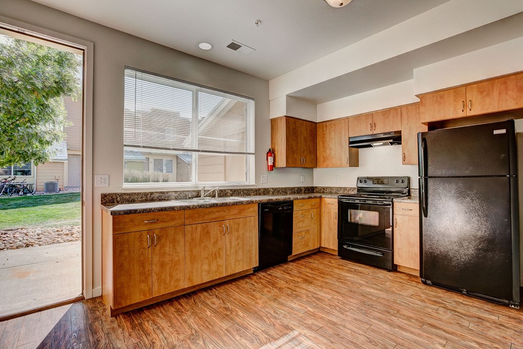 an empty kitchen with wooden cabinets and a black refrigerator