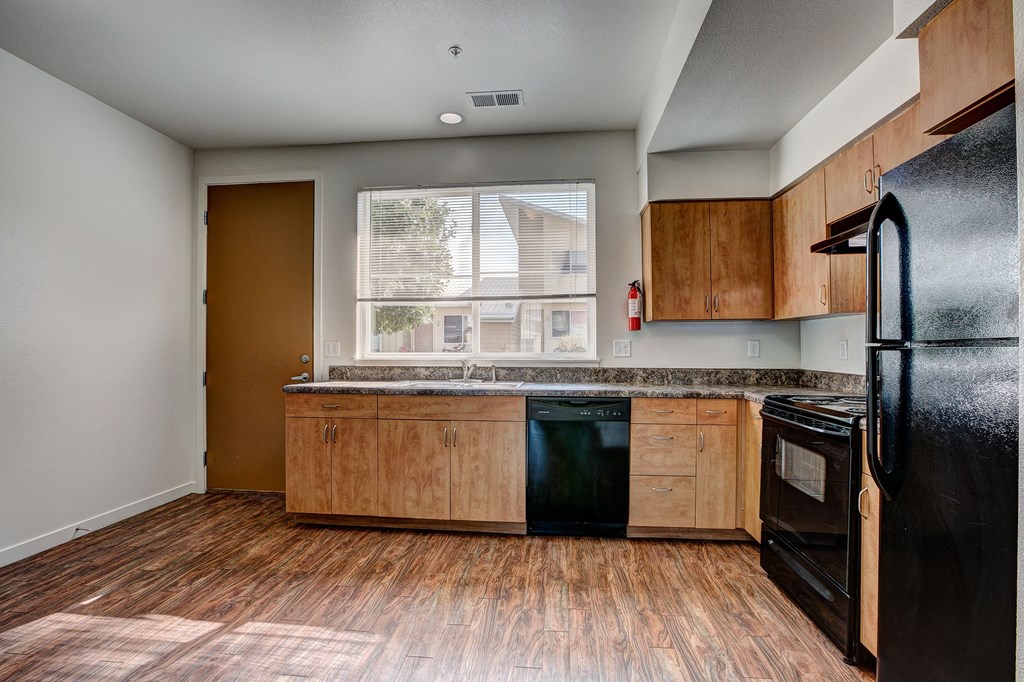 an empty kitchen with wood flooring and a window