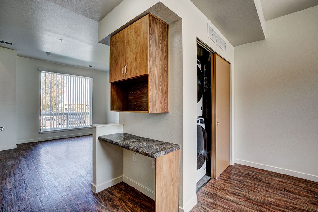 an empty living room with a door to a laundry room with wood flooring