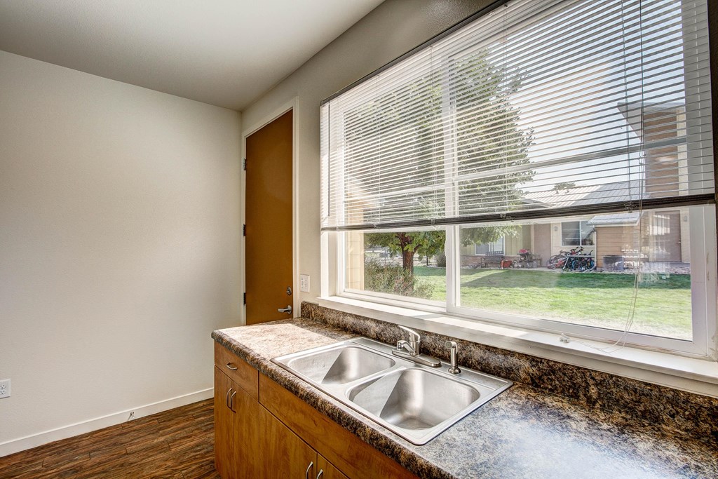 an empty kitchen with a large window and a sink