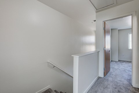 an empty room with a hallway and a door to a bedroom