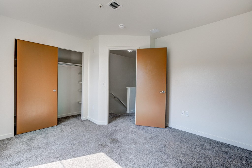 an empty bedroom with doors to a closet and a bathroom