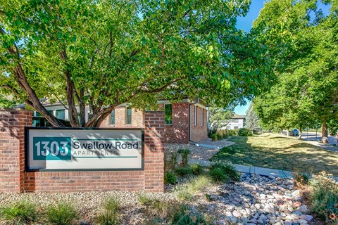 a sign in front of a brick building with a tree