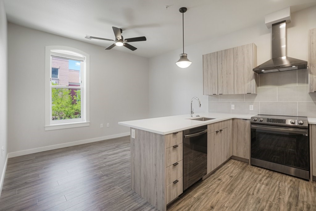 A kitchen with a stove top oven and a fan at The Avenue Lofts Golden Apartments, Colorado, 80401