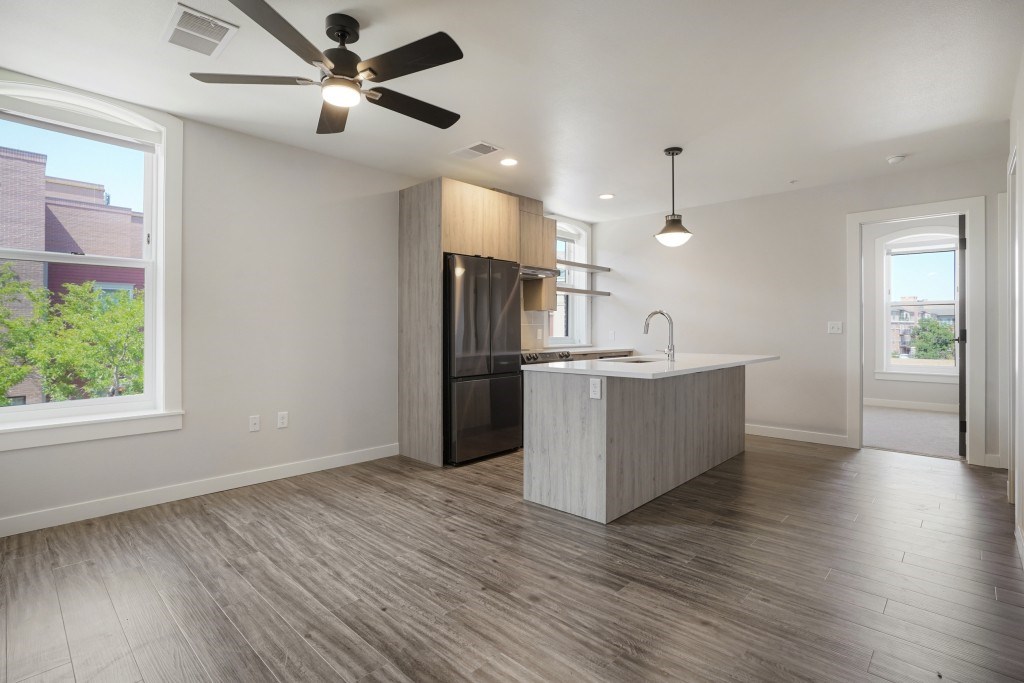 A modern kitchen with a wooden floor and a ceiling fan at The Avenue Lofts Golden Apartments, Golden, CO, 80401