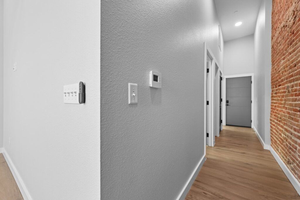 A hallway with a brick wall on the side and a door at the end at The Avenue Lofts Golden Apartments, Golden, Colorado