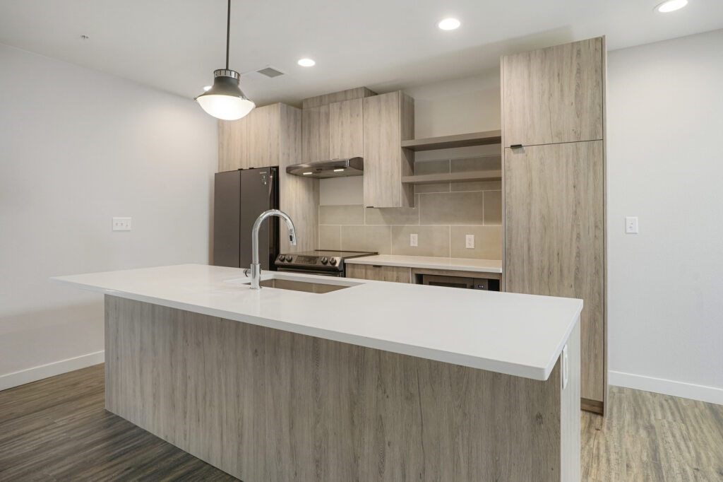 A modern kitchen with a white countertop and wooden cabinets at The Avenue Lofts Golden Apartments, Colorado
