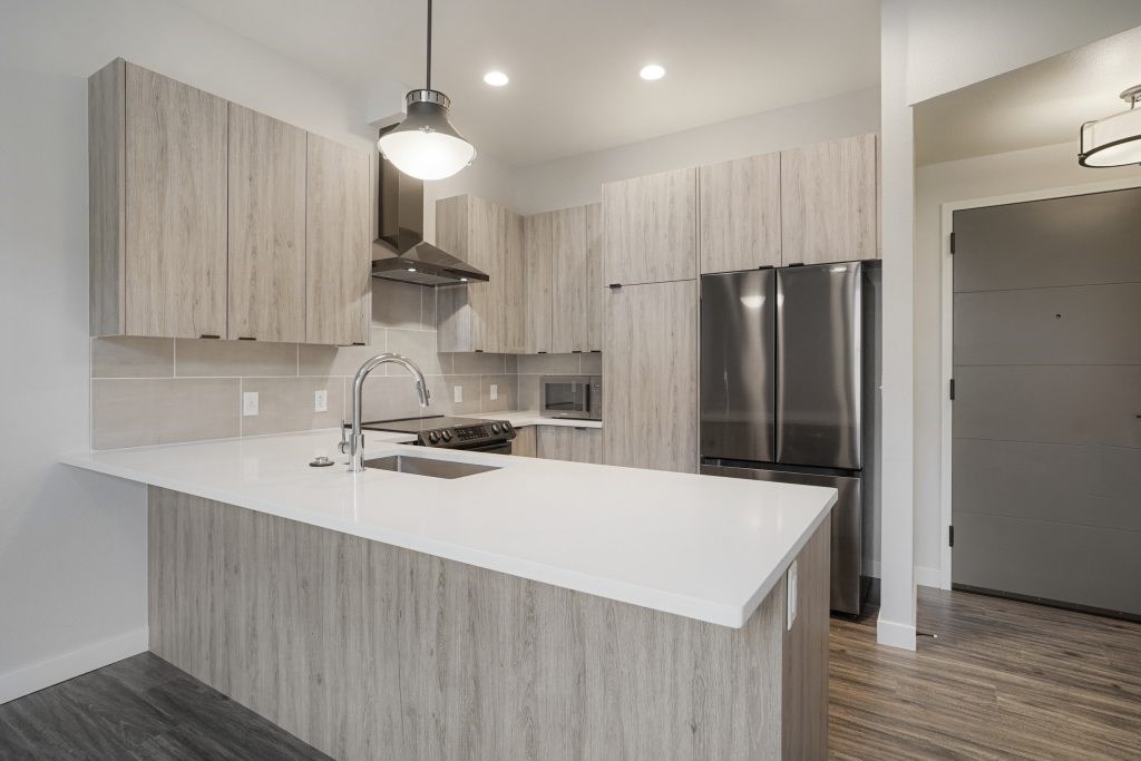 A modern kitchen with a white countertop and wooden cabinets at The Avenue Lofts Golden Apartments, Golden, CO, 80401