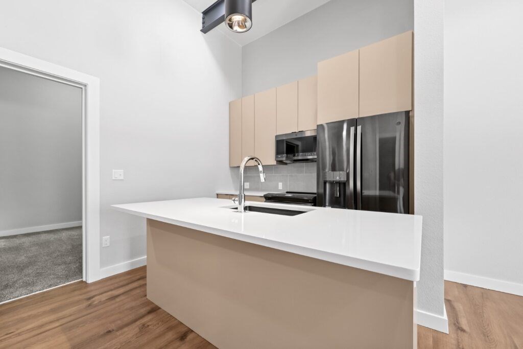 A kitchen with a white counter and beige cabinets at The Avenue Lofts Golden Apartments, Golden, CO, 80401