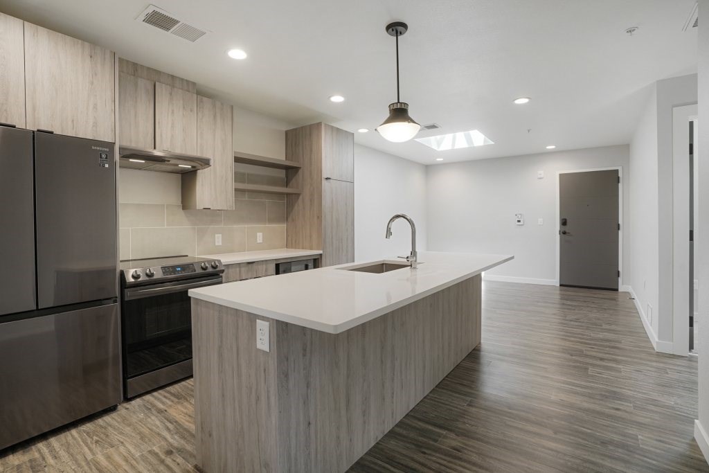A modern kitchen with a stainless steel refrigerator and a wooden island at The Avenue Lofts Golden Apartments, Golden, CO, 80401