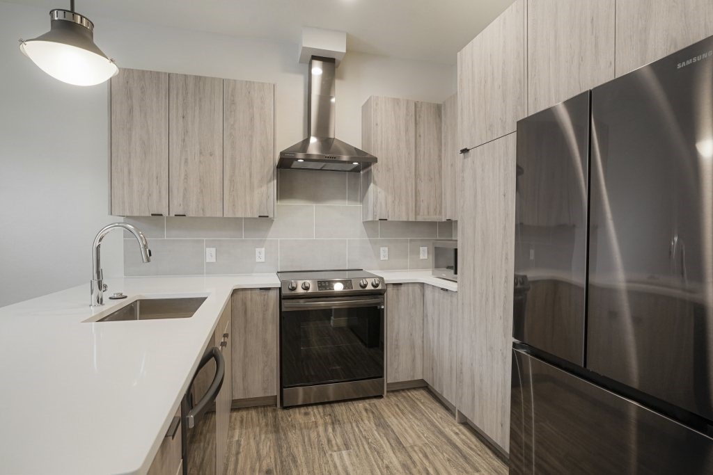 A modern kitchen with a stainless steel refrigerator and wooden cabinets at The Avenue Lofts Golden Apartments, Golden, CO