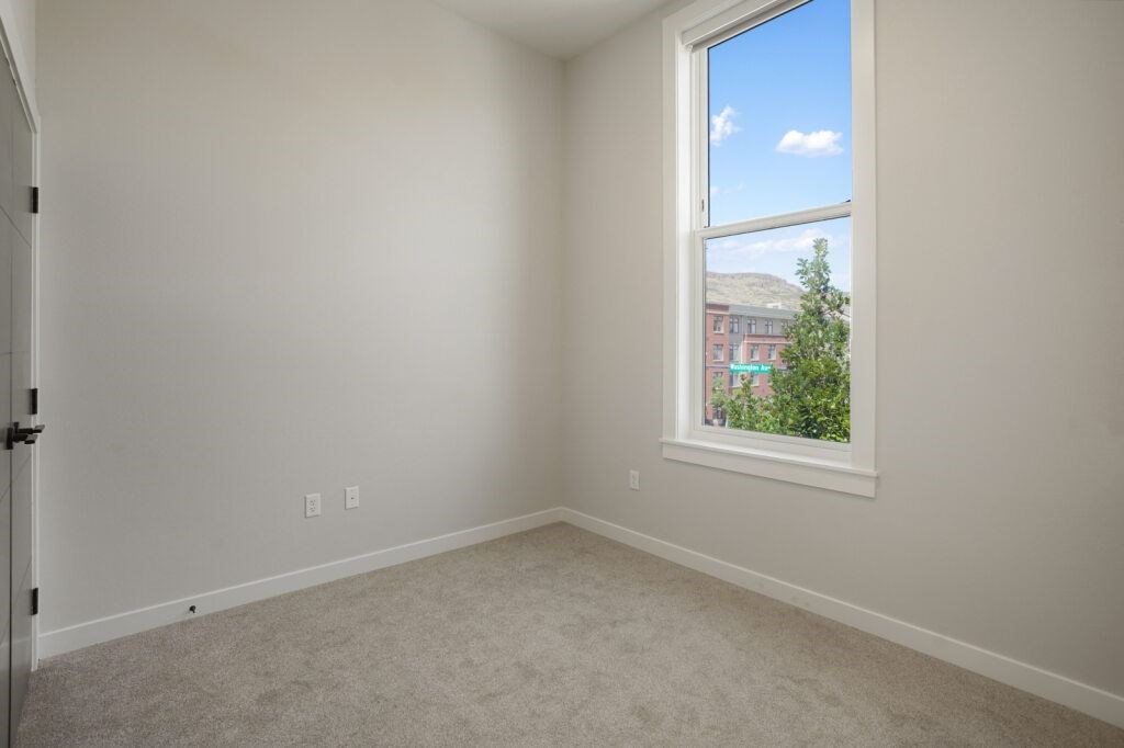 A room with a window overlooking a building and trees at The Avenue Lofts Golden Apartments, Colorado, 80401