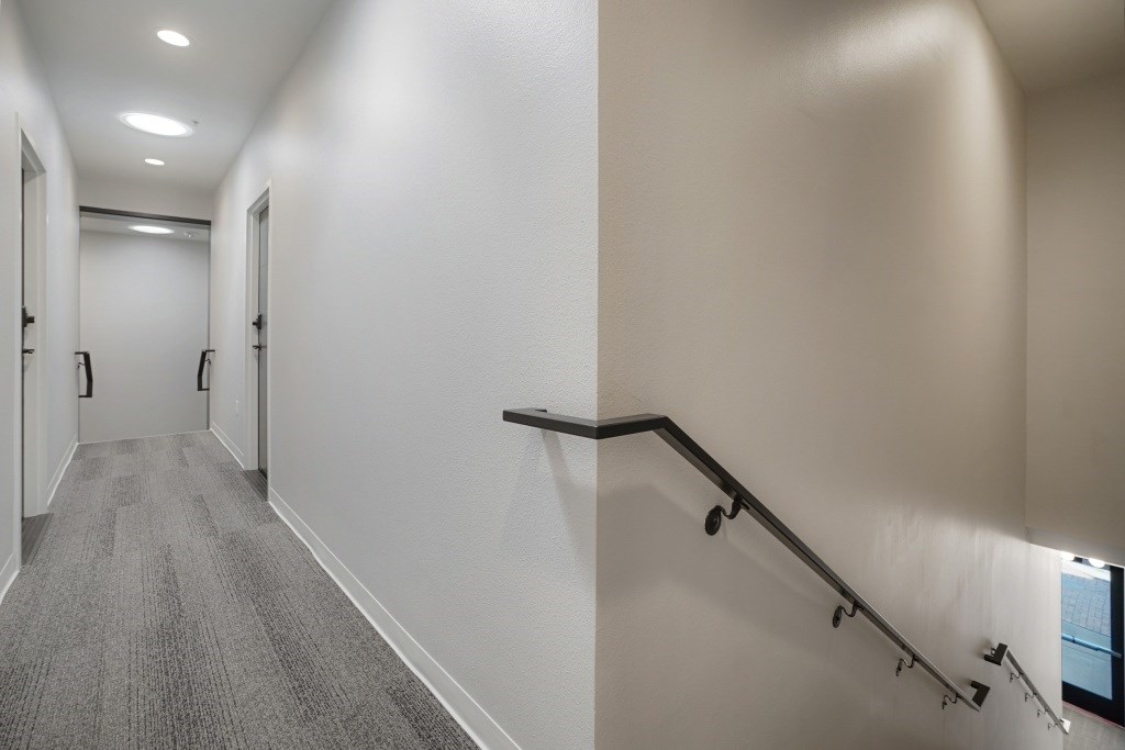 A hallway with a staircase and a carpeted floor at The Avenue Lofts Golden Apartments, Golden 80401