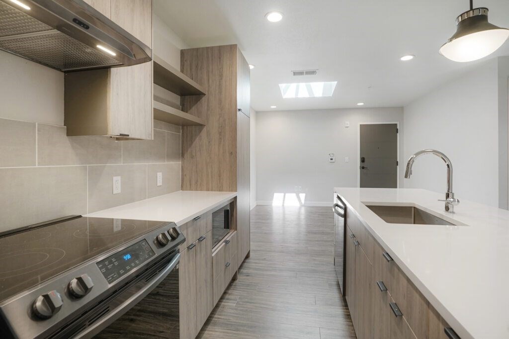 A modern kitchen with a stove top oven and a sink at The Avenue Lofts Golden Apartments, Golden, Colorado