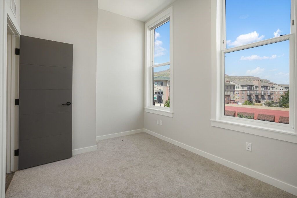 A room with a grey door and a window overlooking a residential area at The Avenue Lofts Golden Apartments, Golden 80401