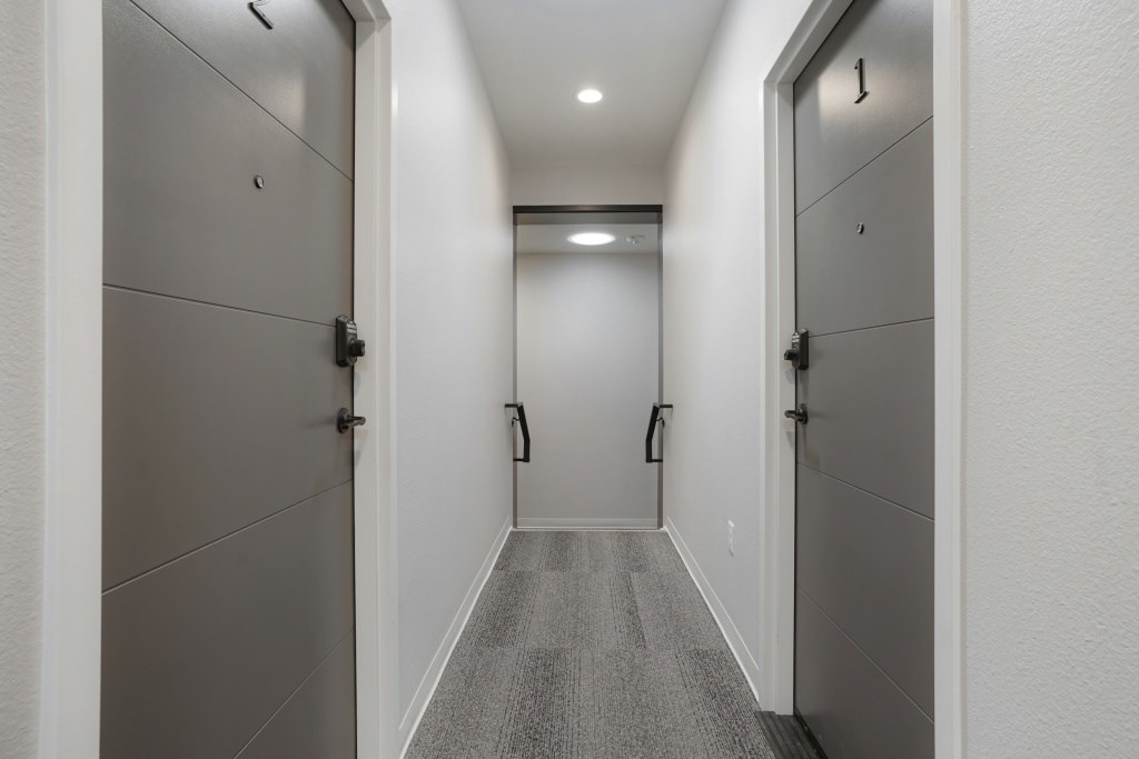 A long hallway with doors on both sides at The Avenue Lofts Golden Apartments, Golden, CO