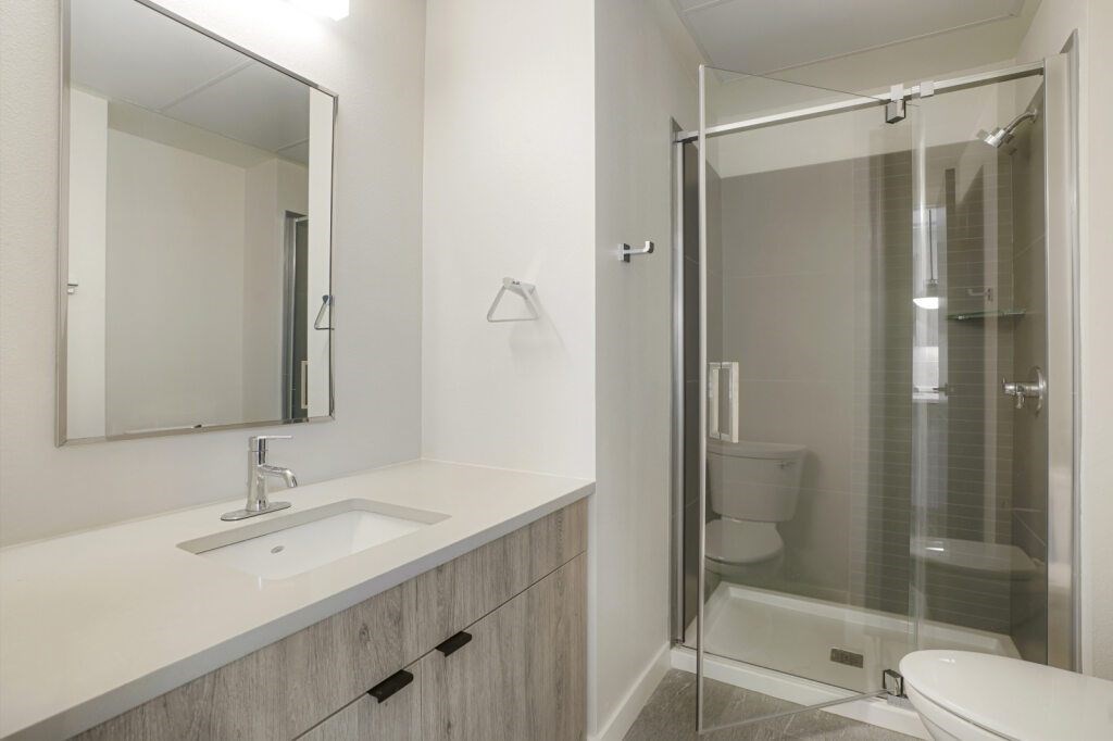 A modern bathroom with a walk-in shower and a white sink at The Avenue Lofts Golden Apartments, Colorado, 80401
