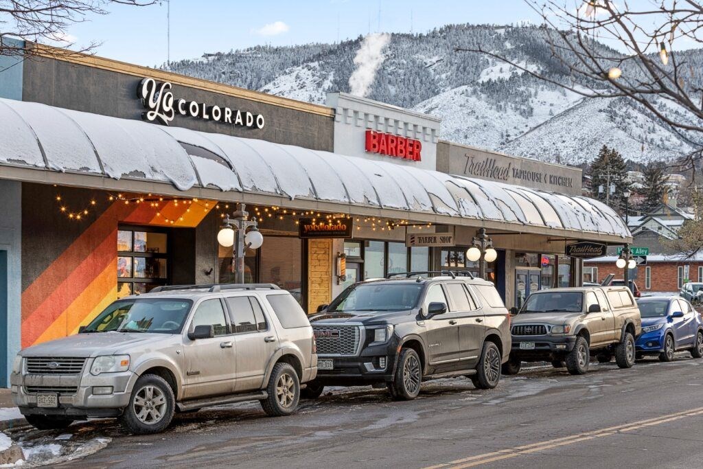 A row of SUVs are parked in front of a barber shop and a yoga studio at The Avenue Lofts Golden Apartments, Colorado, 80401