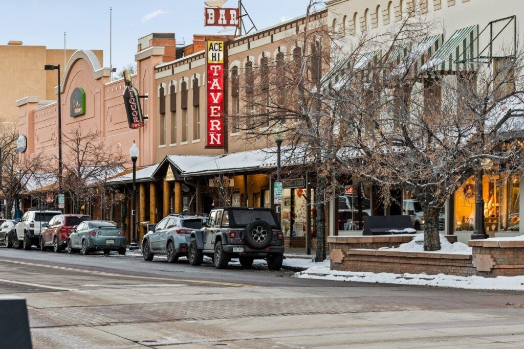 A row of cars parked on the side of a street in front of a tavern at The Avenue Lofts Golden Apartments, Golden, Colorado