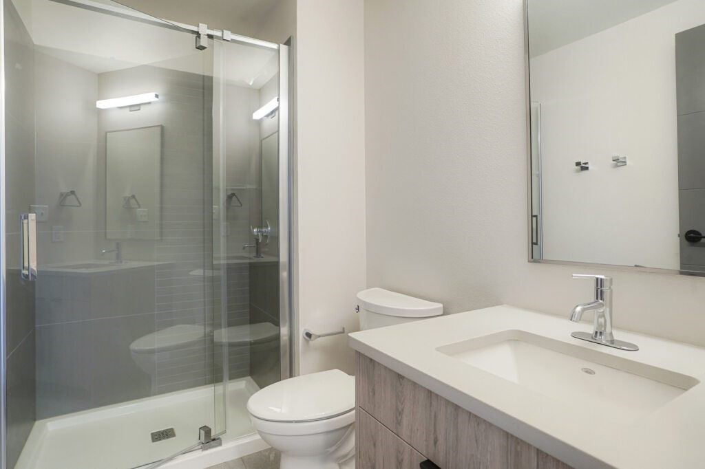 A white toilet sits next to a sink in a bathroom at The Avenue Lofts Golden Apartments, Colorado