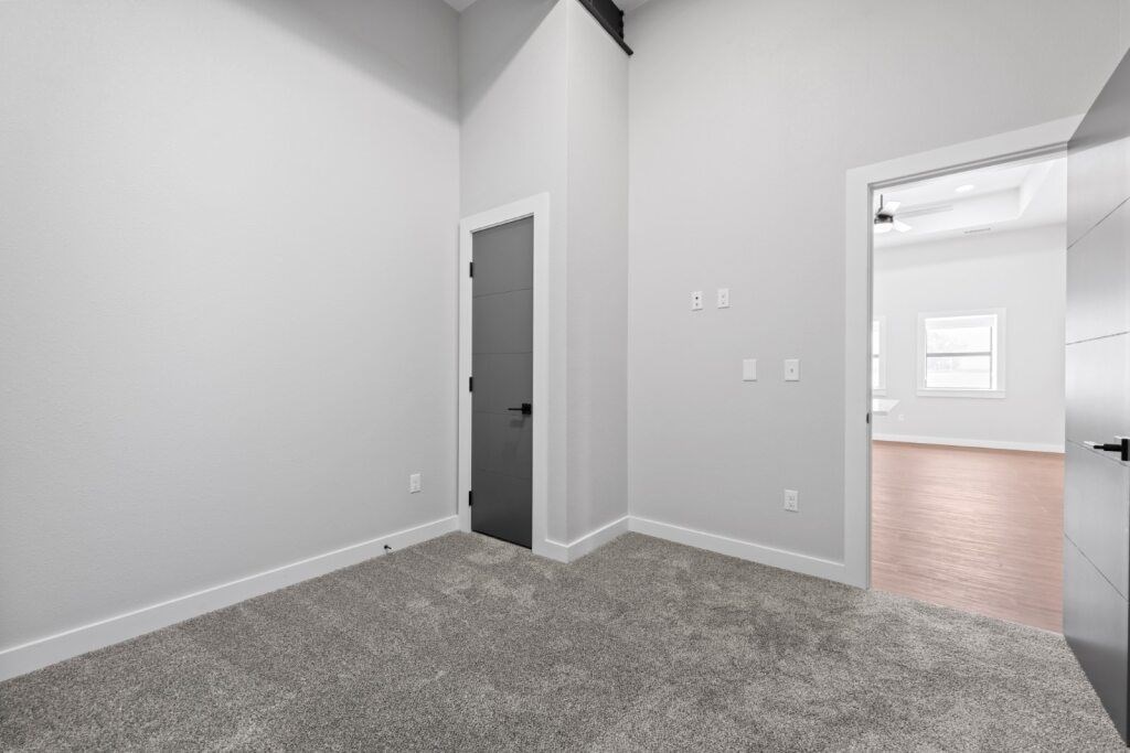 A room with a grey carpet and a grey door at The Avenue Lofts Golden Apartments, Golden, Colorado