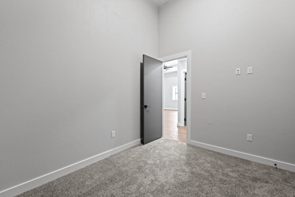 A room with a carpeted floor and a door at The Avenue Lofts Golden Apartments, Golden, Colorado
