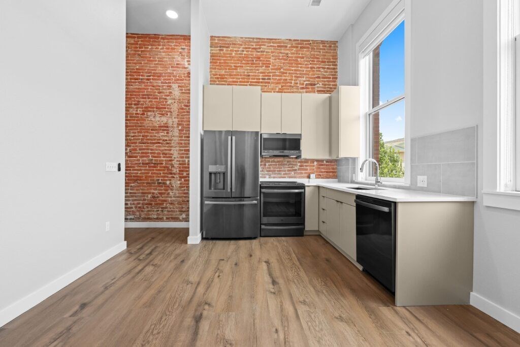 A kitchen with a red brick wall and wooden floors at The Avenue Lofts Golden Apartments, Golden