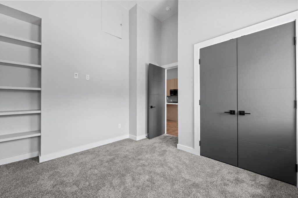 A room with a grey carpet and a grey wardrobe at The Avenue Lofts Golden Apartments, Golden, Colorado