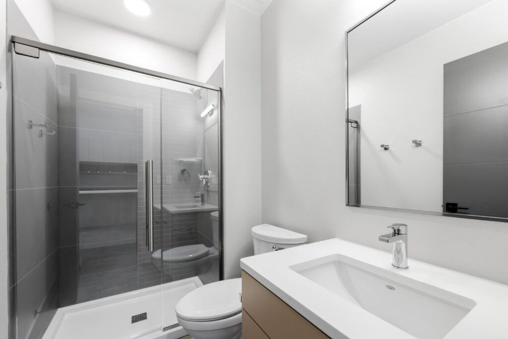 A modern bathroom with a walk-in shower and a white sink at The Avenue Lofts Golden Apartments, Colorado, 80401