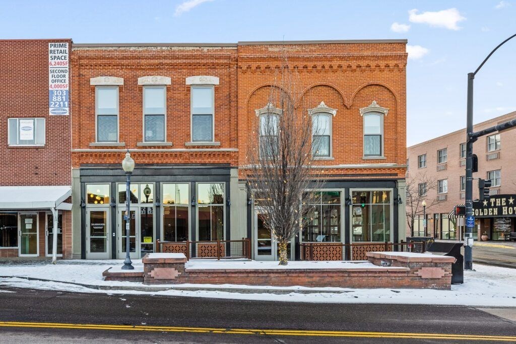 A red brick building with a sign at The Avenue Lofts Golden Apartments, Golden, CO, 80401