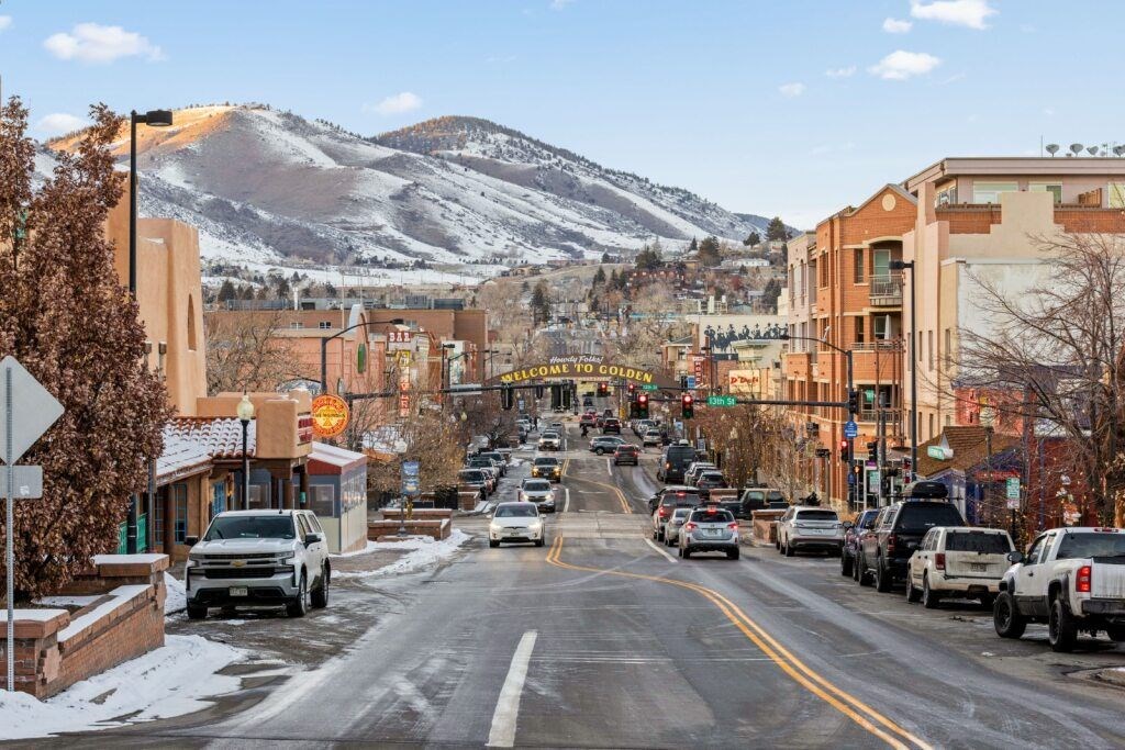A street with cars parked on the side and a mountain in the background at The Avenue Lofts Golden Apartments, Golden, CO, 80401