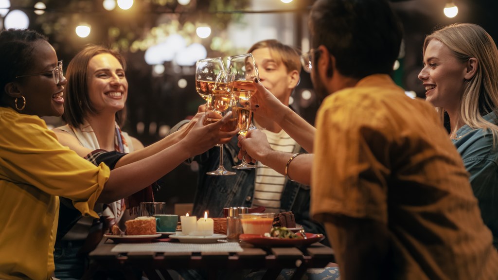 A group of people toasting with glasses of wine at a dinner table at The Avenue Lofts Golden Apartments, Colorado, 80401