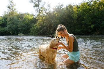 A woman is playing with her dog in the water at The Avenue Lofts Golden Apartments, Golden, CO, 80401