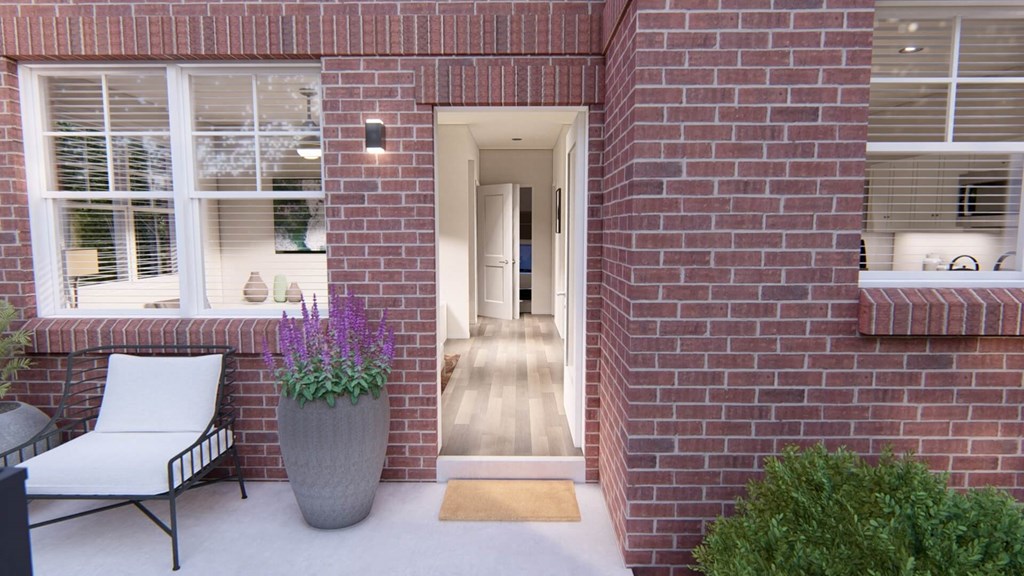 a red brick house with a porch and a large gray planter with purple flowers at Brownstones at Palisade Park, Broomfield, CO