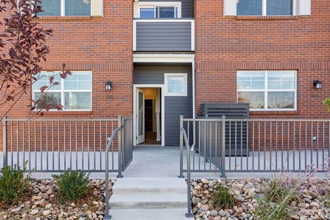 Townhome entrance with patio and metal handrails at Brownstones at Palisade Park Apartments, Broomfield, Colorado